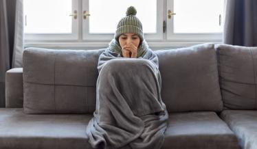 dame avec un plaid qui a froid sur son canapé