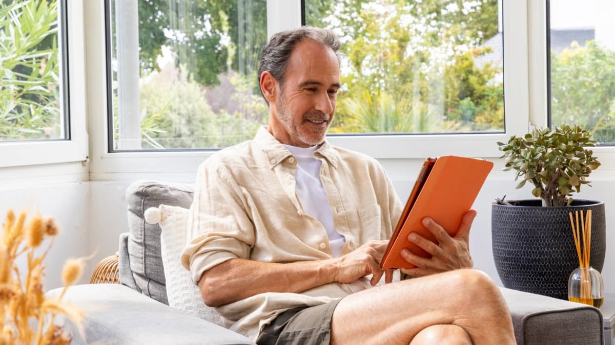 homme assis sur un fauteuil qui consulte sa tablette