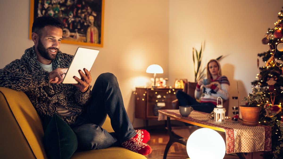 homme dans son salon qui consulte sa tablette